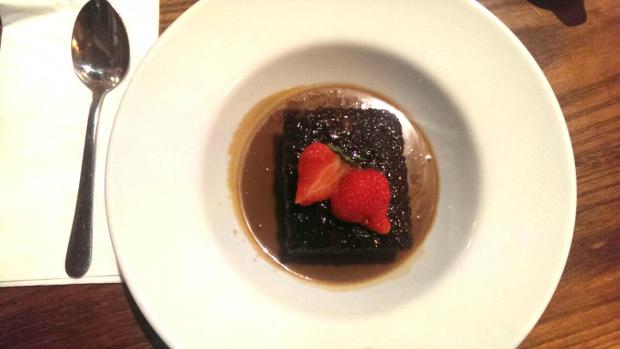 Scrumptious Sticky Toffee Pudding with a pool of Custard and a strawberry on top!